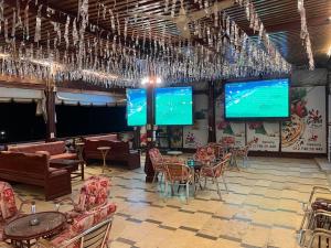 a restaurant with tables and chairs and large screens at Grand Plaza Apartment in Marsa Alam City +26 photos