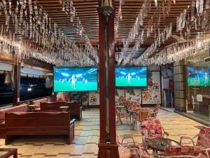 a restaurant with couches and tables and televisions at Grand Plaza Apartment in Marsa Alam City