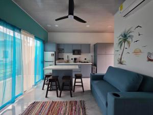 a living room with a blue couch and a kitchen at The Palm at Life's a Beach in Uvita