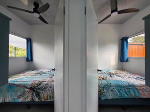 a bedroom with two beds and two windows at The Palm at Life's a Beach in Uvita
