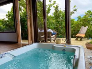 a tub in a room with a view of a patio at Hospedaria Ponta da Piteira in Imbituba