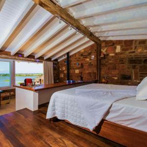 a bedroom with a bed and a stone wall at Hospedaria Ponta da Piteira in Imbituba +101 photos
