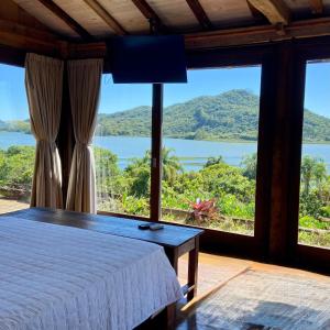 a bedroom with a bed and a view of a lake at Hospedaria Ponta da Piteira in Imbituba