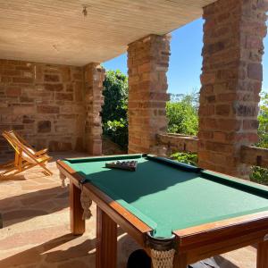 a pool table in an outdoor room with a brick wall at Hospedaria Ponta da Piteira in Imbituba