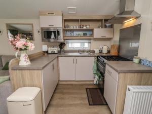 a small kitchen with white cabinets and a sink at Homeslea 33 Millennium Gardens in Morpeth