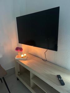 a flat screen tv on a wall with a remote control at Apartamentos luz de Doñana 1 in Moguer