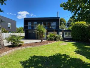 a house with a black facade with a yard at The Rock House, Patons Rock in Rangihaeata