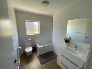 a white bathroom with a sink and a toilet at The Rock House, Patons Rock in Rangihaeata +17 photos