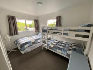 a bedroom with two bunk beds and a window at The Rock House, Patons Rock in Rangihaeata