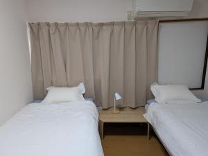 a room with two beds and a window with curtains at marusan houseマルさんの家 in Osaka