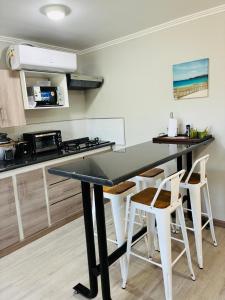 a kitchen with a table and some white stools at Florencia Boutique Cabin in Olmué