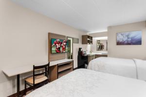 a hotel room with a bed and a desk and a television at Red Roof Inn PLUS Chicago - Hoffman Estates in Hoffman Estates