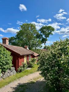 a small house with a stone wall and trees at Heritage-listed country cottages in Eskilstuna