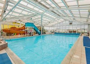 a large indoor swimming pool with a slide and a water park at Sandy Haven in Ingoldmells