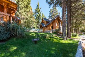 a sign in the grass in front of a log cabin at Bosque Dormido Cabañas & Spa in San Carlos de Bariloche