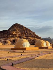 three domes in the desert with a mountain in the background at Star Gate Camp in Wadi Rum