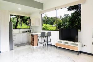 a kitchen with white cabinets and a large window at La Danta Lodge - Rio Celeste in Bijagua