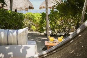 a chair and a table with two drinks on a beach at Beachfront Bliss Suite in Balcheil