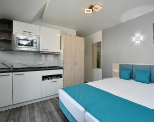 a bedroom with a large bed and a kitchen at City-Hotel Zuffenhausen - Apartments in Stuttgart