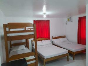 two bunk beds in a room with red curtains at Dandal Bay view in El Nido