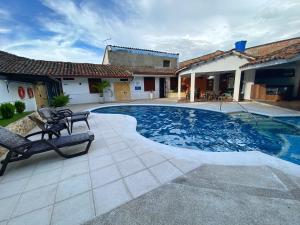 a swimming pool with two chairs and a house at Hotel Casa Antigua Buga in Buga