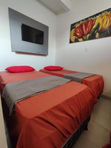 two beds in a room with a tv on the wall at Quarto Triplo Comercial - Queen's Hotel in Formosa