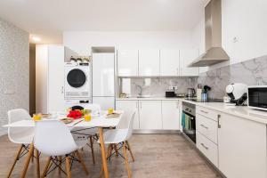 a kitchen with white cabinets and a table and chairs at Sol Blessing by GALMI in Ponta do Sol