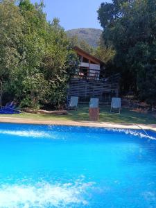 a house with two chairs in front of a swimming pool at Casa Olmué in Olmué