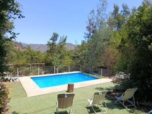 a swimming pool in a yard with two chairs at Casa Olmué in Olmué