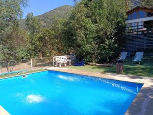 a swimming pool with blue water in front of a house at Casa Olmué in Olmué