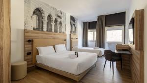 a hotel room with two beds and a desk at B&B HOTEL Como Baradello in Como