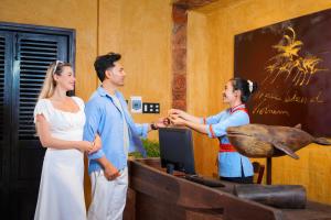 a man and two women shaking hands in a room at Whale Island Resort in Dam Mon