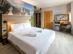 a hotel room with a large white bed and a television at B&B HOTEL Latina in Latina