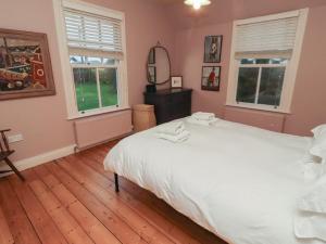 a bedroom with a large white bed and two windows at Armstrong Cottages No6 in Bamburgh