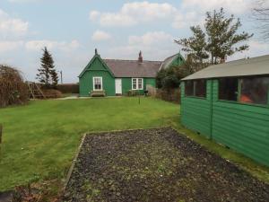 a green and white house with a yard at Armstrong Cottages No6 in Bamburgh