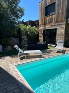 a swimming pool with two lounge chairs next to a house at L'Immortelle in Zonza