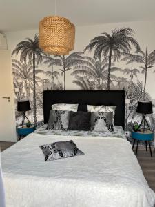 a bedroom with a bed with palm trees on the wall at L'Immortelle in Zonza