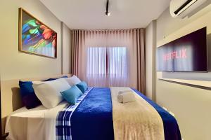 a bedroom with a large bed with blue and white pillows at Studio Prime, no centro de CWB in Curitiba