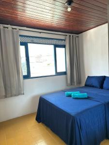 a bedroom with a bed with blue sheets and a window at CASA MARAGOGI 3 Quartos in Maragogi