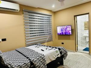 a bedroom with a bed and a flat screen tv at T-Roys Apartments in Accra