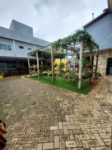 a patio with trees and tables and a building at Quarto Triplo Comercial - Queen's Hotel in Formosa