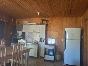 a kitchen with white appliances and a wooden ceiling at Casa da praia sulmar in Balneário Gaivotas