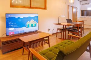 a living room with a tv and a couch and a table at North Nagano Inn in Iiyama