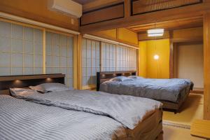 two beds in a room with yellow walls at North Nagano Inn in Iiyama