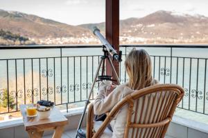 a woman sitting in a chair looking out a window at Lakeview Balcony in Kastoria in Kastoria