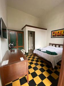 a bedroom with a bed and a desk and a checkerboard floor at Hotel Casa Antigua Buga in Buga