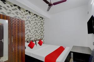 a bedroom with a white bed with red pillows at Hotel O ALISHA LODGE in Āsansol