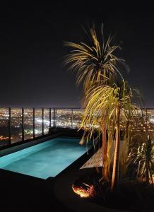 a pool on the roof of a building with a palm tree at Condomínio Residencial - Hype 017 | by Housi in Sao Jose do Rio Preto