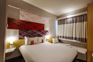 a bedroom with a large white bed in a room at Ibis Maringa in Maringá +269 photos