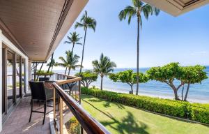 a balcony with a view of the ocean and palm trees at Puunoa Beach Estate in Lahaina
